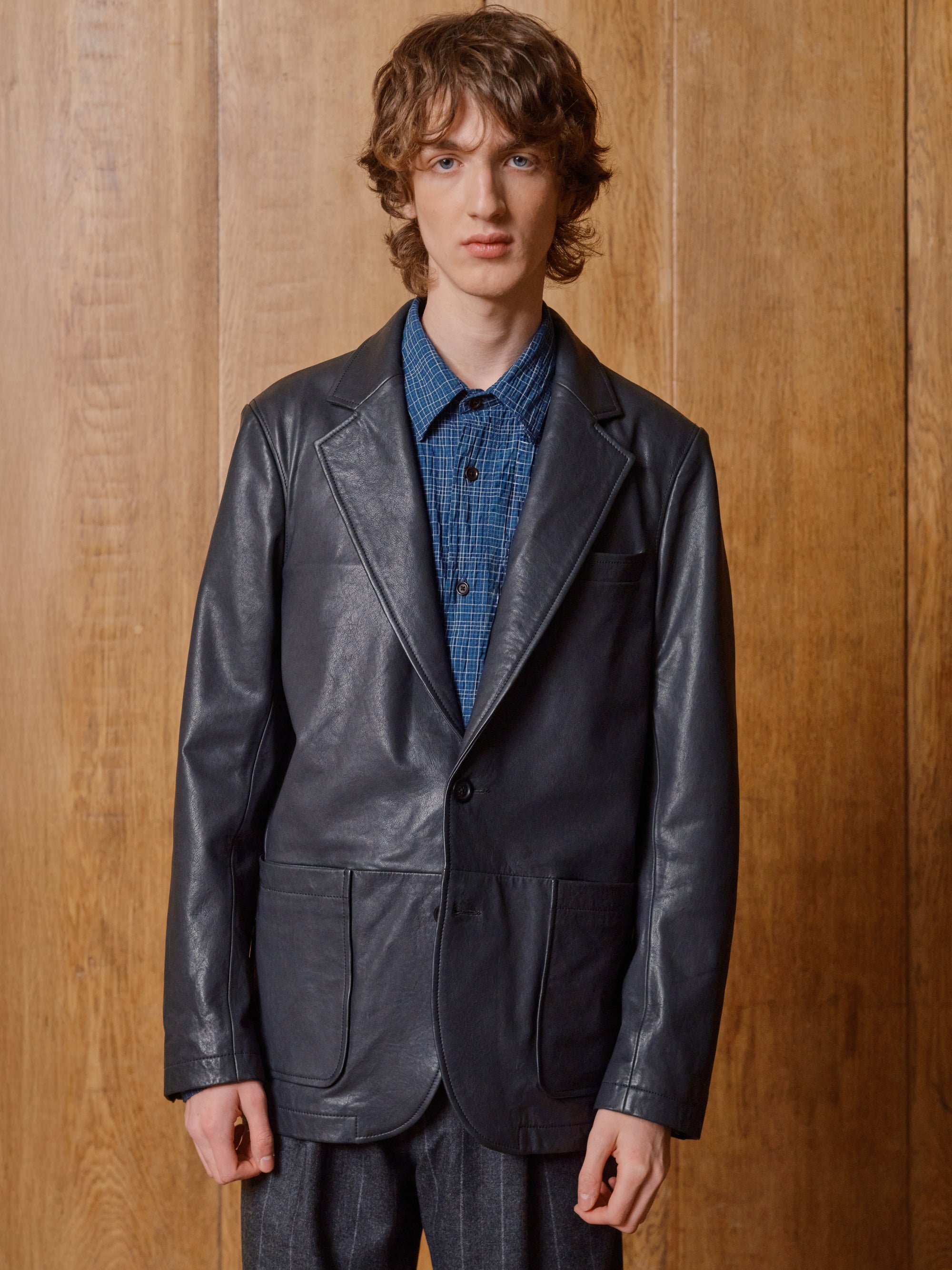 Model in a black leather jacket and blue check shirt